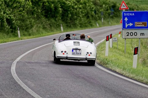 A white vintage convertible on an open country road towards Siena, vintage car, car race, Mille