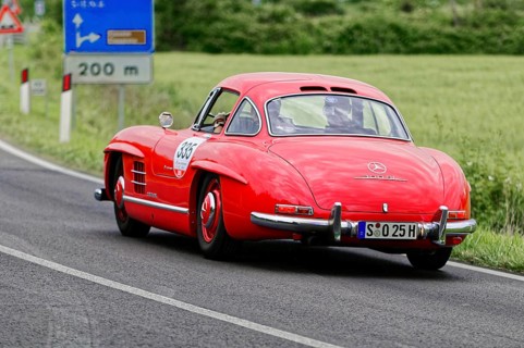 A red Mercedes classic car is seen from behind on a country road, classic car, car race, Mille