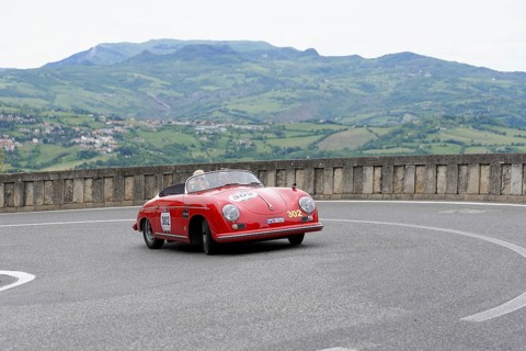 Red open-top sports car on a winding track in a picturesque mountain landscape, Mille Miglia 2014