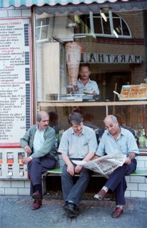 Berlin, DEU, 10.06.1998 -- Turkish men sit reading newspapers in front of a kebab shop. (Free time,