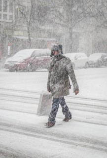 DEU Germany Germany Berlin People in the city during a snow shower.Pedestrian crosses snowy road