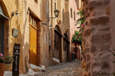 Narrow paved path in the old town with flowering plants and old buildings, Monemvasia, Monemvassia,