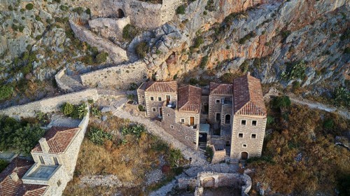 Drone view, aerial view of an ancient fortress with stone houses and vegetation on rocky terrain,