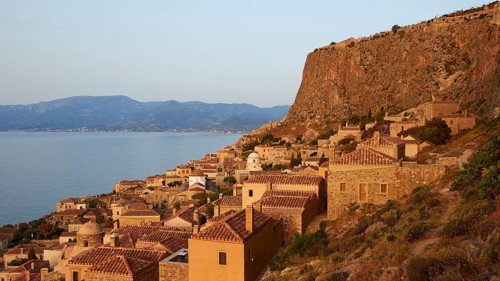 Soft morning light, traditional Mediterranean buildings on a rock overlooking the coastline in