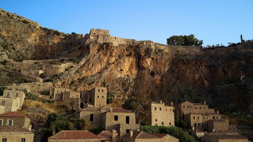 Drone shot, medieval buildings on a rocky cliff overlooking the Mediterranean Sea at sunset,