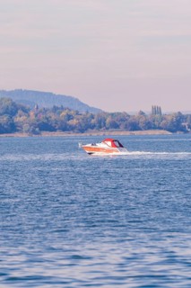 A motorboat sails at high speed across a quiet lake in autumn surroundings, boat trip, Lake