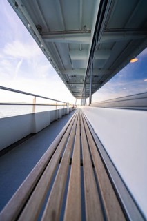 Long ship deck with wooden bench, looking out to sea, with a clear sky above, boat trip, Lake