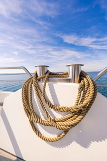 Thick ropes carefully draped on the boat deck in front of a wide sky and sea view, boat trip, Lake
