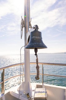 Ship bell on the bow of a boat, shining against the blue sky over calm sea, boat trip, Lake