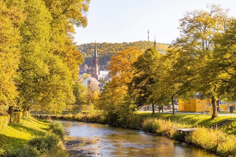 Autumn river landscape with a church and colorful trees in the background, Nagold, Black Forest,