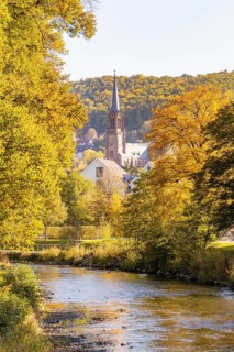 River landscape with a view of a church and autumn trees in a small village, Nagold, Black Forest,