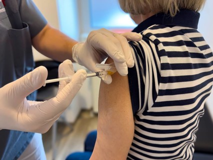 Patient woman receives injection in upper arm for vaccination against contagious disease flu flu