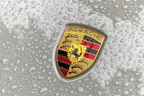 Coloured Porsche crest on sports car bonnet with sparkling raindrops, international