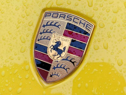 Colored Porsche crest on yellow sports car bonnet with sparkling raindrops, international