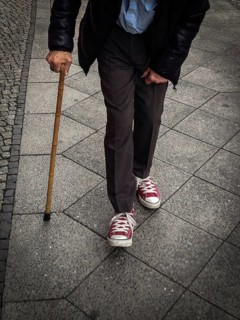 DEU Germany Germany Berlin Old man with a crutch walking through the German capital wearing