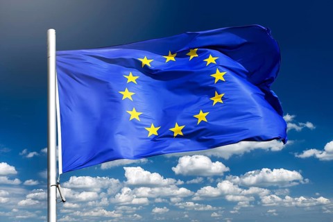 European Union flag waving against blue sky, photo montage