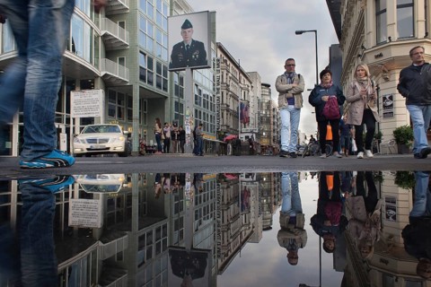 DEU Germany Germany Berlin Tourists at Checkpoint Charlie reflecting in a puddle after rain