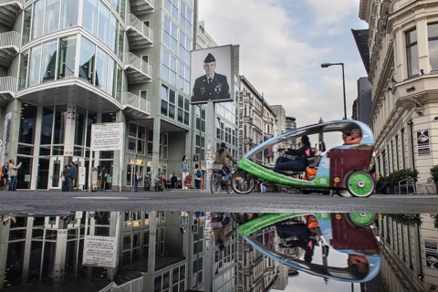 DEU Germany Germany Berlin Tourists at Checkpoint Charlie reflecting in a puddle after rain