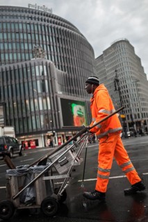 DEU Germany Berlin An employee of Stadtreinigung BSR pushes his handcart across a block of