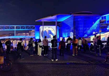 Passers-by watch the projection To the German People — A Parliamentary Search for Clues at the