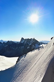 Mountaineers climb over a snow-covered ridge, behind Grandes Jorasses, Aiguille du Midi mountain