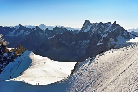 Mountaineers climb over a snow-covered mountain ridge, behind Grandes Jorasses, viewing platform,