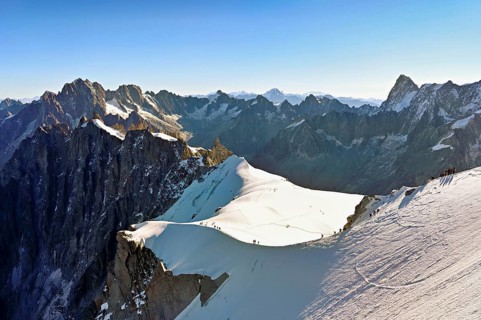 Mountaineers climb over a snow-covered ridge, behind Aiguille Verte, Les Droites, Les Courtes,
