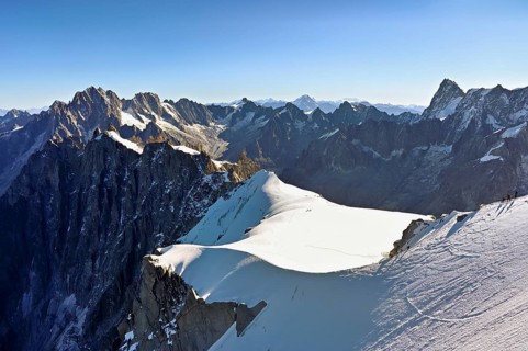 Mountaineers climb over a snow-covered ridge, behind Aiguille Verte, Les Droites, Les Courtes,