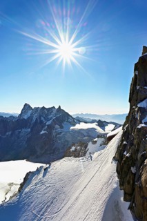 Mountaineers climb over a snow-covered ridge, behind Grandes Jorasses, Aiguille du Midi mountain
