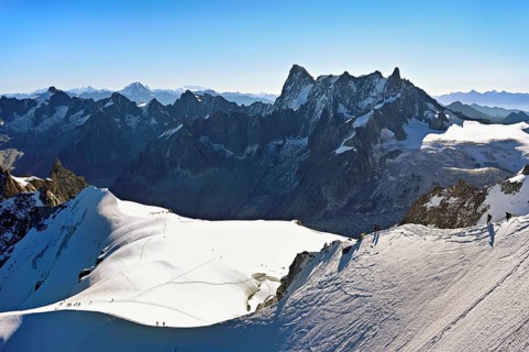Mountaineers climb over a snow-covered mountain ridge, behind Grandes Jorasses, viewing platform,