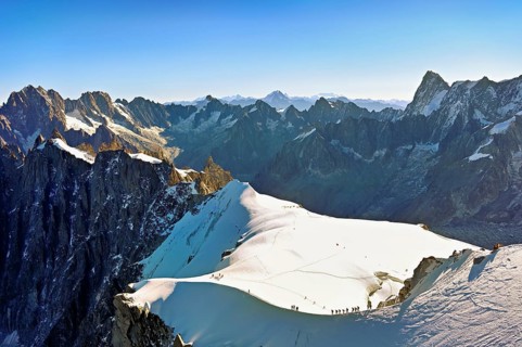 Mountaineers climb over a snow-covered ridge, behind Aiguille Verte, Les Droites, Les Courtes,