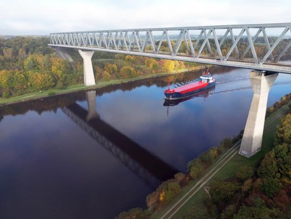 Cargo ship sails under the Grünental High Bridge in autumn through the Kiel Canal, NOK, Kiel Canal,