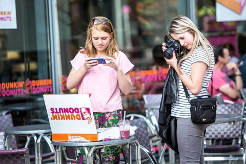 DEU Germany Germany Berlin Girls photograph a box of donuts they just bought in front of a Dunkin