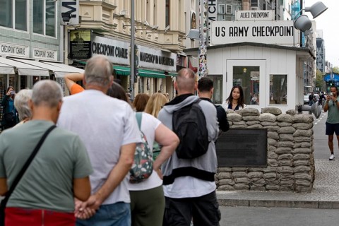 Tourists at Checkpoint Charlie queue for a souvenir photo, Berlin, Germany