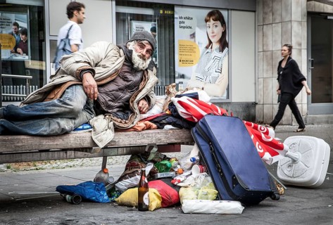 DEU Germany Germany Berlin A homeless person sits on a bench next to his belongings in a square in