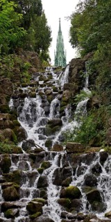 Artificial waterfall in Victoria Park, with the national monument on Kreuzberg in the background,