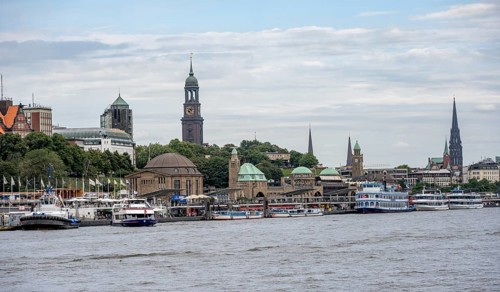Elbe and boats at the St. Pauli piers, historic building with a level tower, in the back church