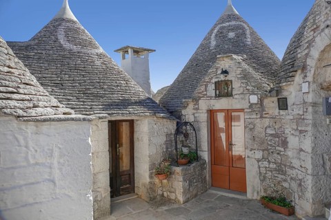Sunny impression of trulli houses at a town named Alberobello in Apulia, Italy