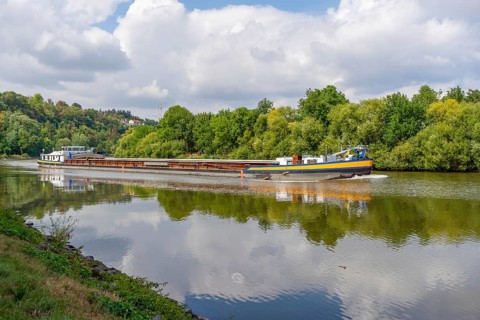 Cargo ship on a river at summer time in sunny ambiance