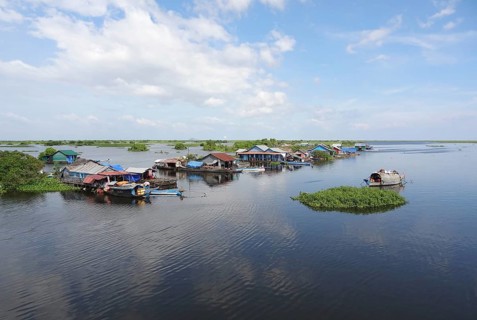 Waterside scenery with rural houses and boats at the Tonle Sap, a river in Cambodia