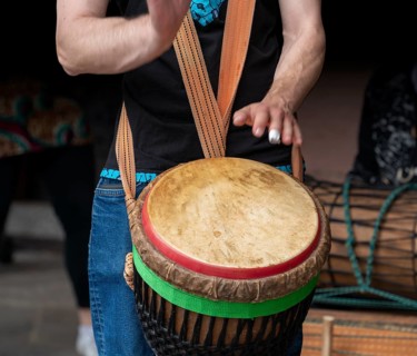 Detail of a djembe drum player in dark back