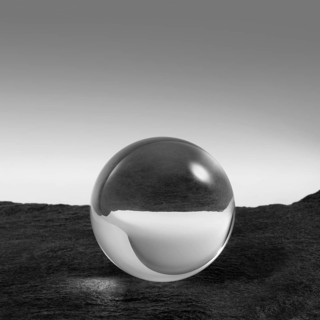 A clear crystal ball on rough dark grey stone surface in front of red back