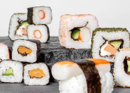 Various sushi dishes on dark grey stone surface