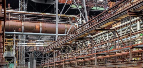 Weathered rundown industrial scenery with old corroded steel girders and metal tubes
