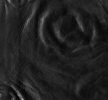 Full frame abstract background showing a old black rippled leather surface