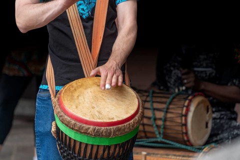 Detail of a djembe drum player in dark back