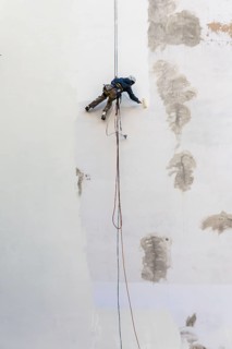 DEU Germany Germany Berlin A worker painting a façade while hanging from a rope