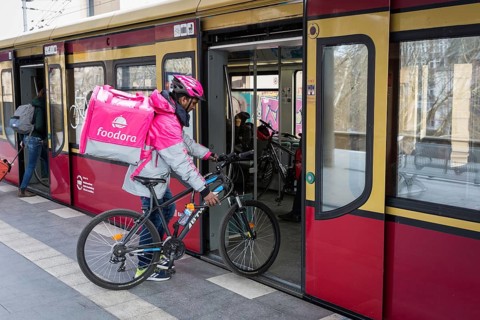 DEU Germany Germany Berlin A Foodora food courier boards an S-Bahn train with his equipment