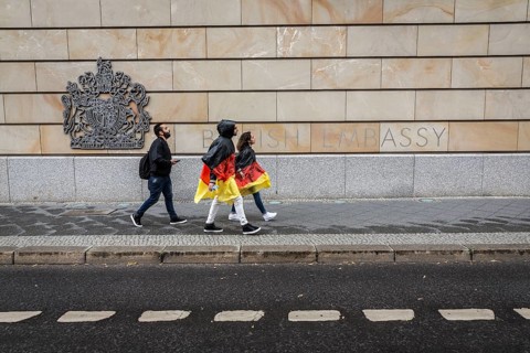 DEU Germany Germany Berlin Two tourists with rain capes in the colours of Germany pass the British