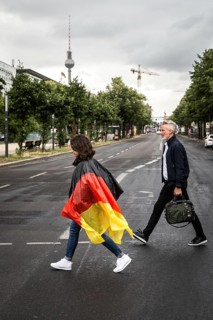 DEU Germany Germany Berlin Tourist with rain capes in the colours of Germany crosses a pedestrian
